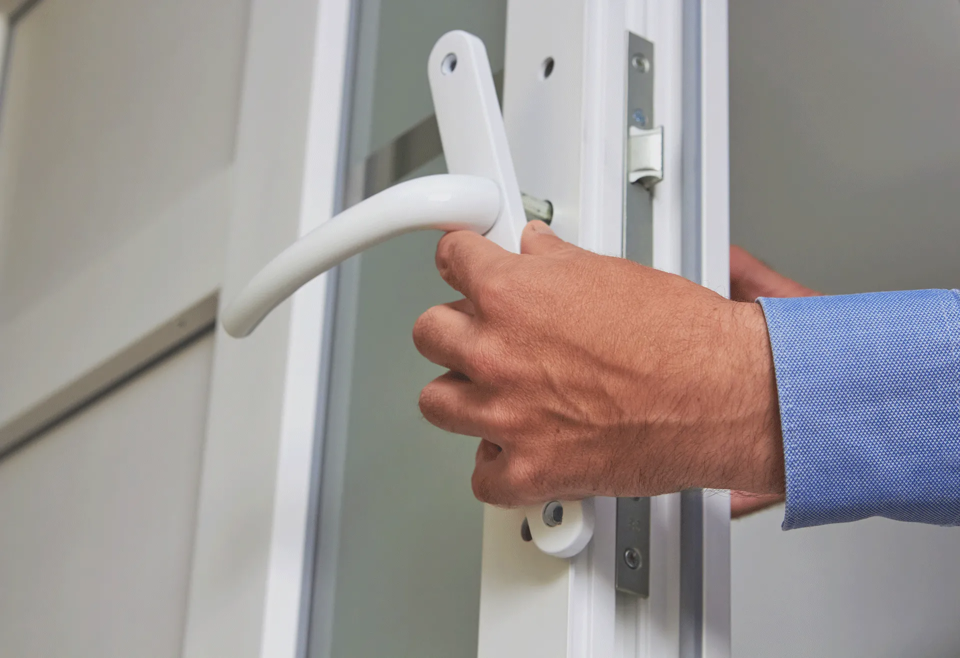 Locksmith fixing a broken white door handle after picking a lock.